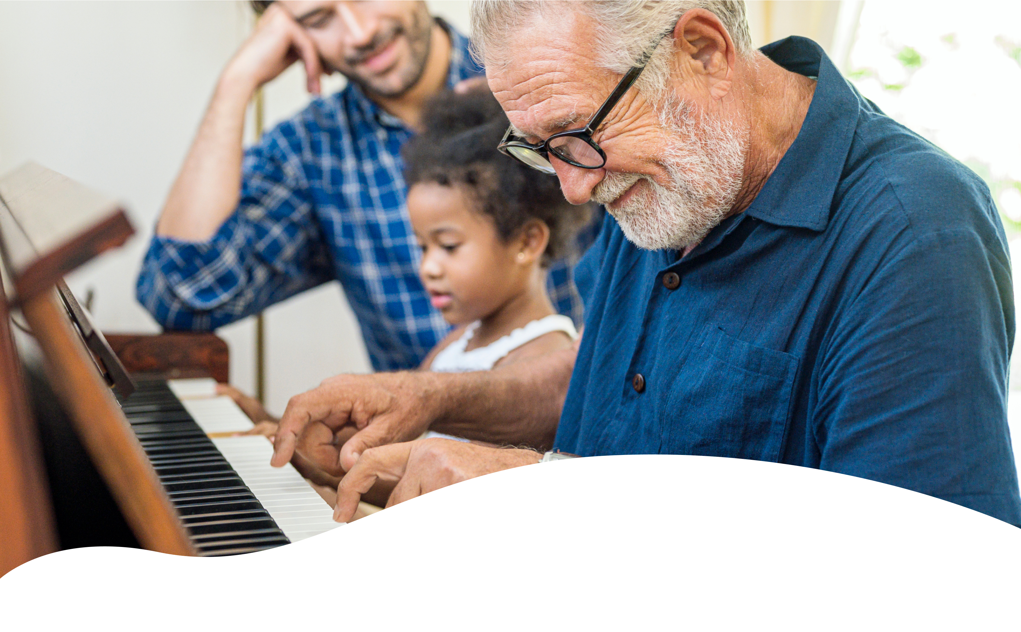 Smiling 55+ man with a child and a younger man at a piano