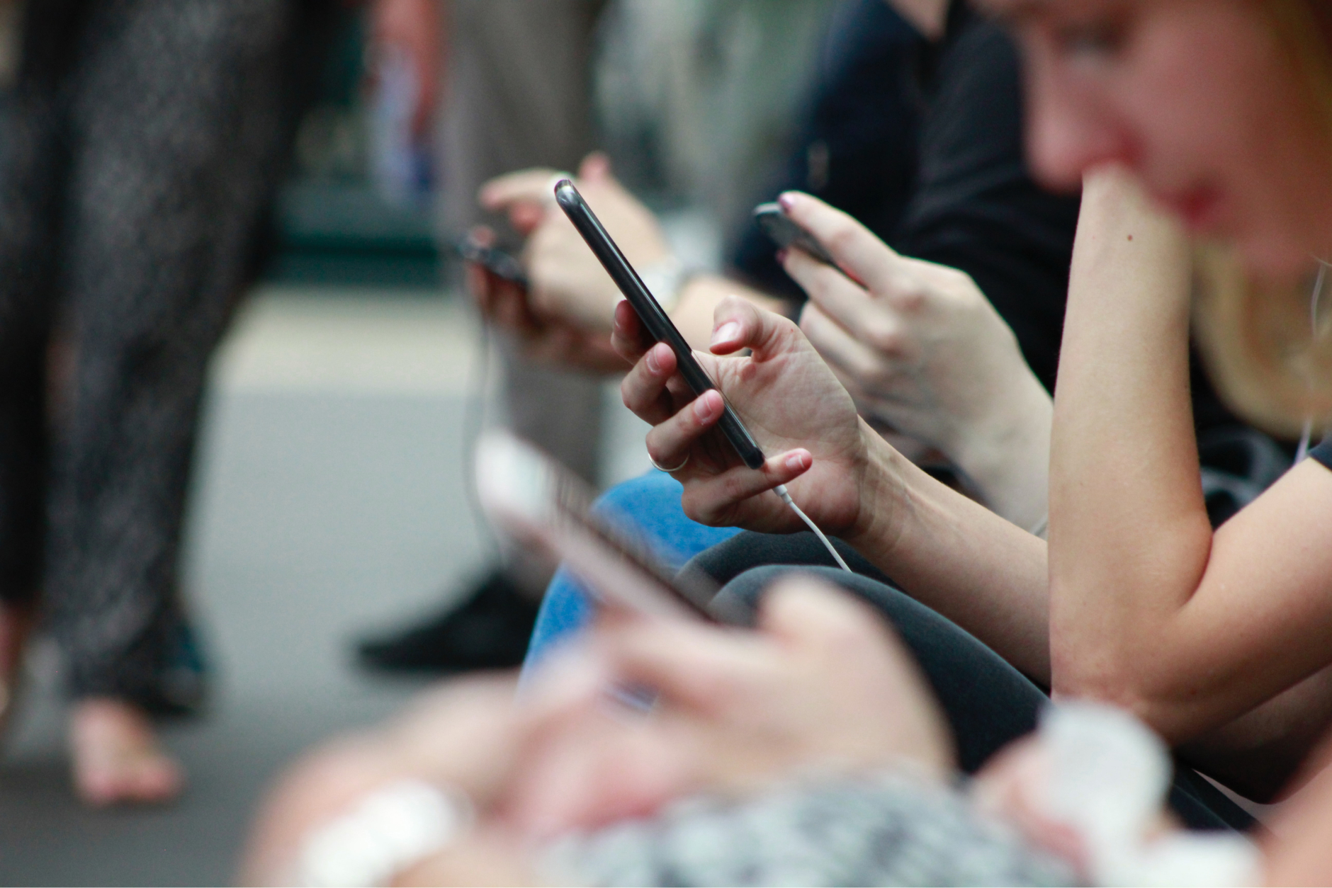 Closeup of several people’s hands holding cell phones; inset of digital media dashboards